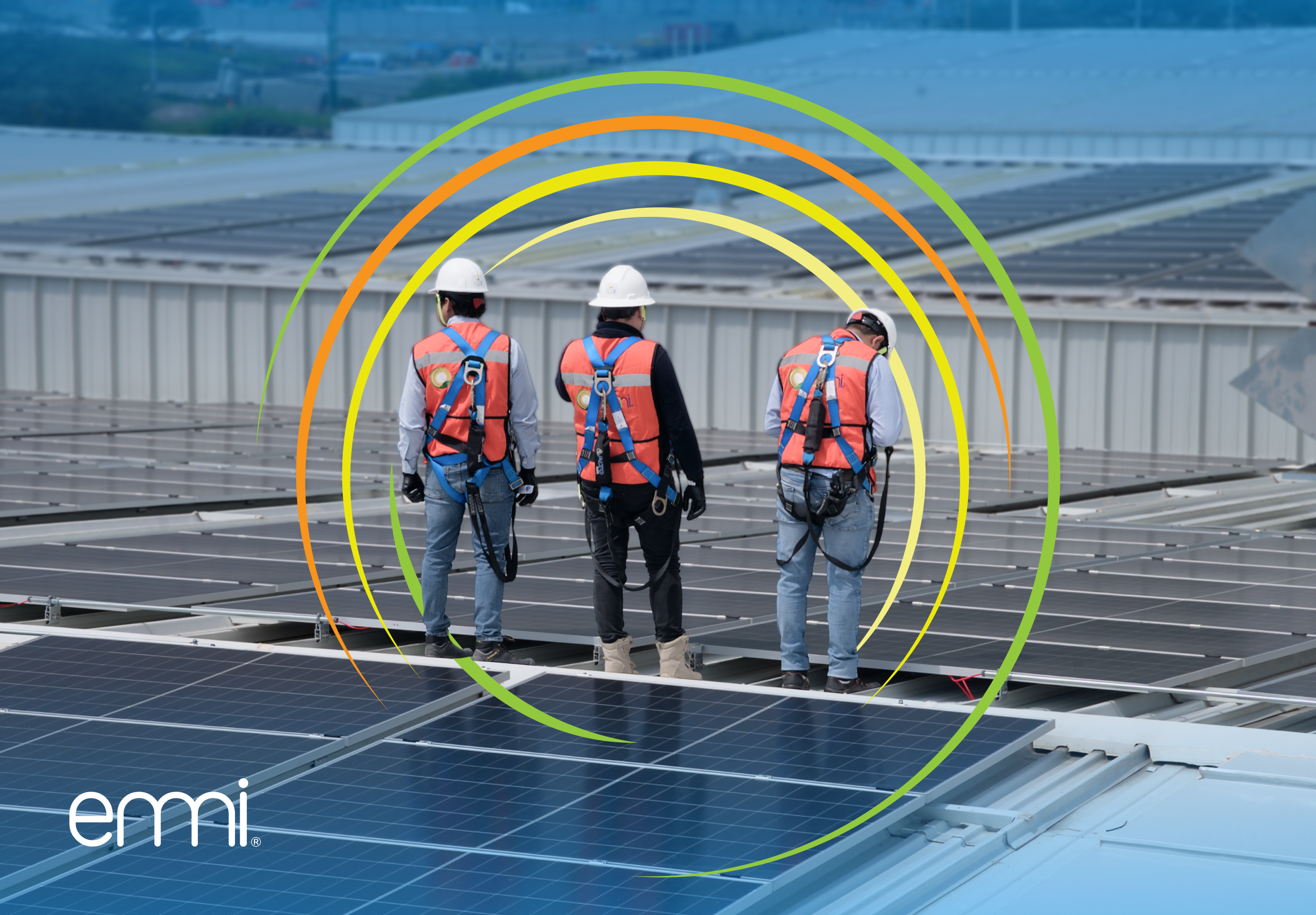 Tres técnicos de EMMI con equipo de seguridad supervisando la instalación de paneles solares en una planta industrial de gran escala.